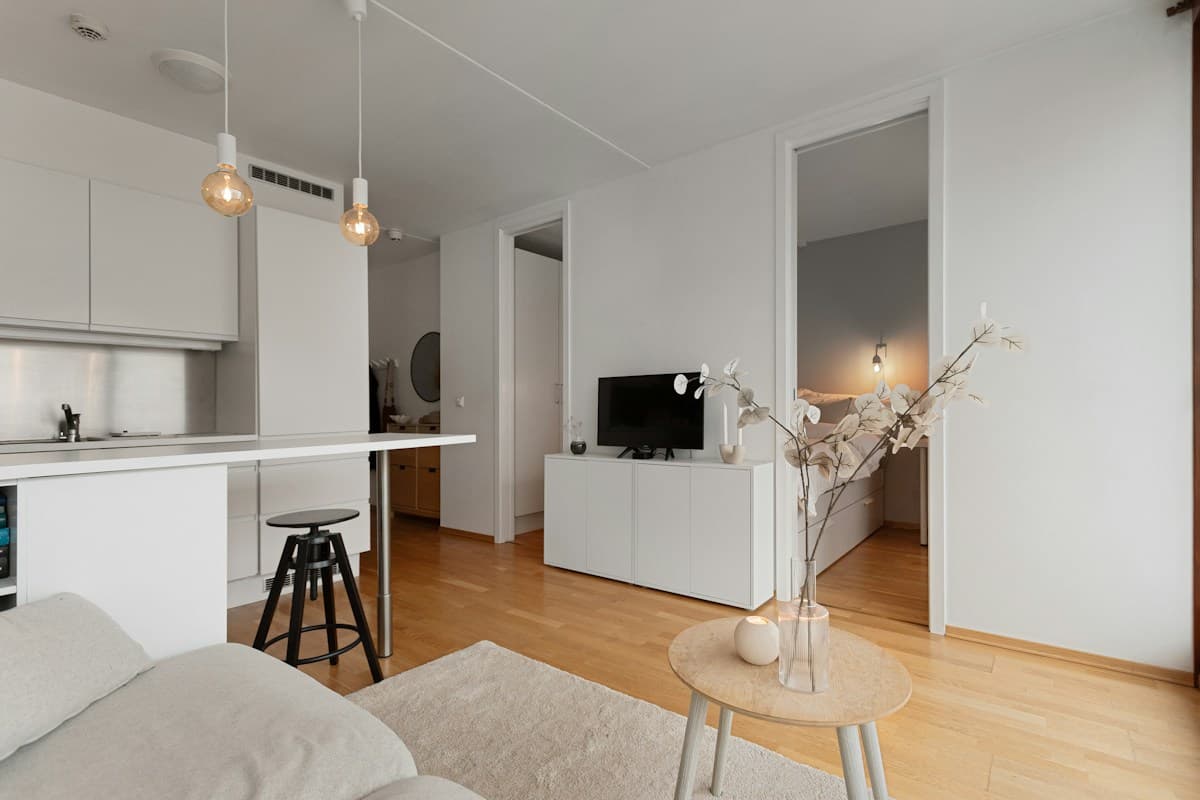 Apartamento pequeno e claro com sala integrada à cozinha, piso de madeira e móveis simples